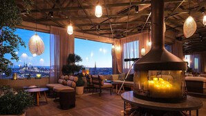 Un área de descanso acogedora con una chimenea grande, asientos cómodos y vistas a la ciudad.