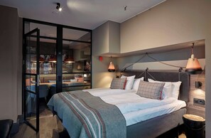 A modern bedroom with a large bed, a desk, and a seating area.