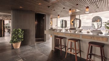 A modern kitchen with a large island, bar stools, and a potted plant.