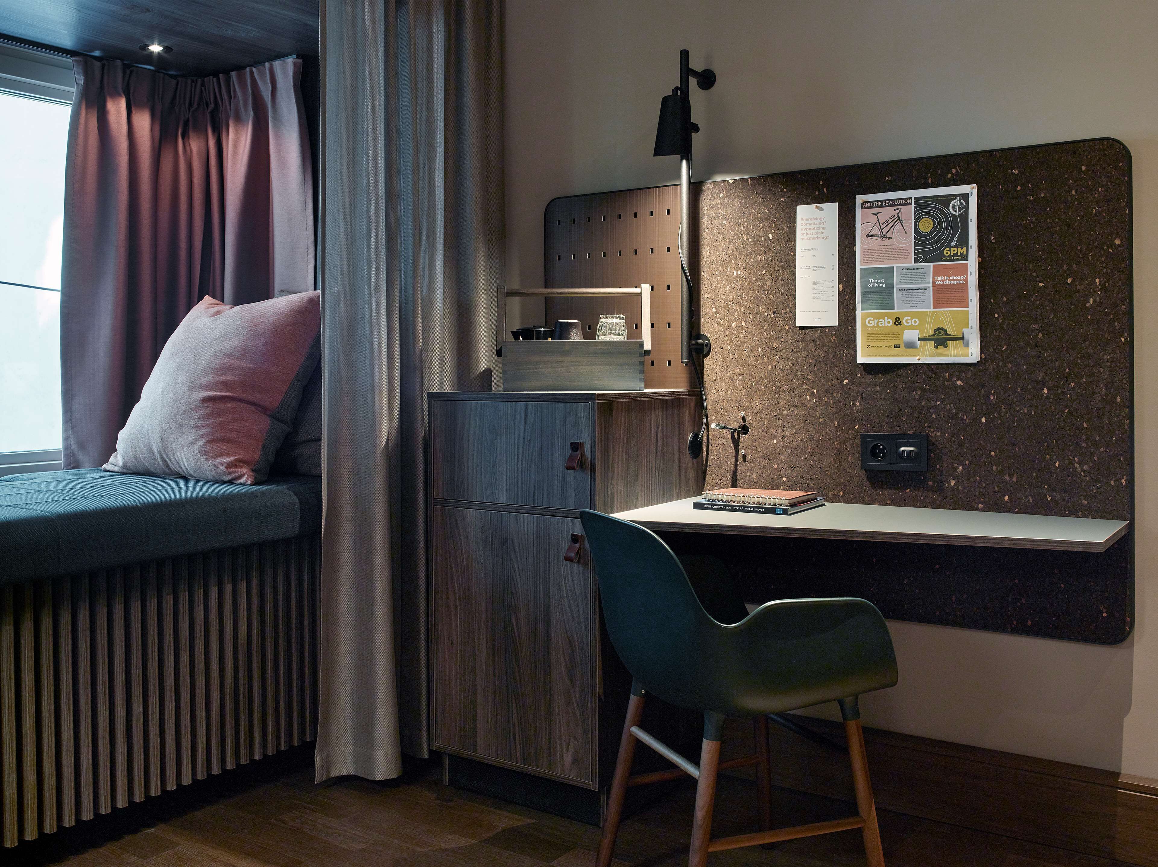 Quarto moderno com cama, escrivaninha, cadeira e um mural com diversos avisos.