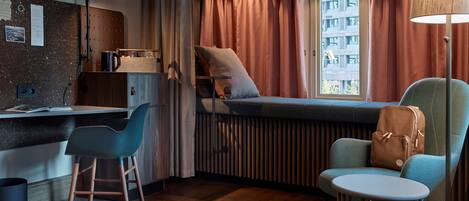 Una habitación de hotel moderna con cama, escritorio, silla y vista a la ciudad.