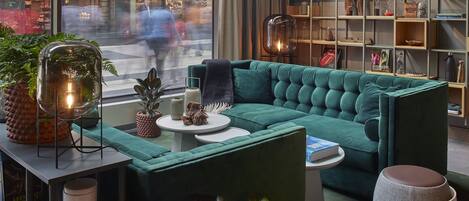 Una sala de estar moderna con un sofá color turquesa, una mesa redonda de centro y una estantería llena de libros y objetos decorativos.