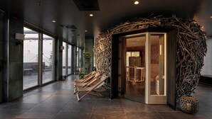 Un interior moderno con entrada de puerta de cristal, un banco de madera y una pared decorada con ramas.