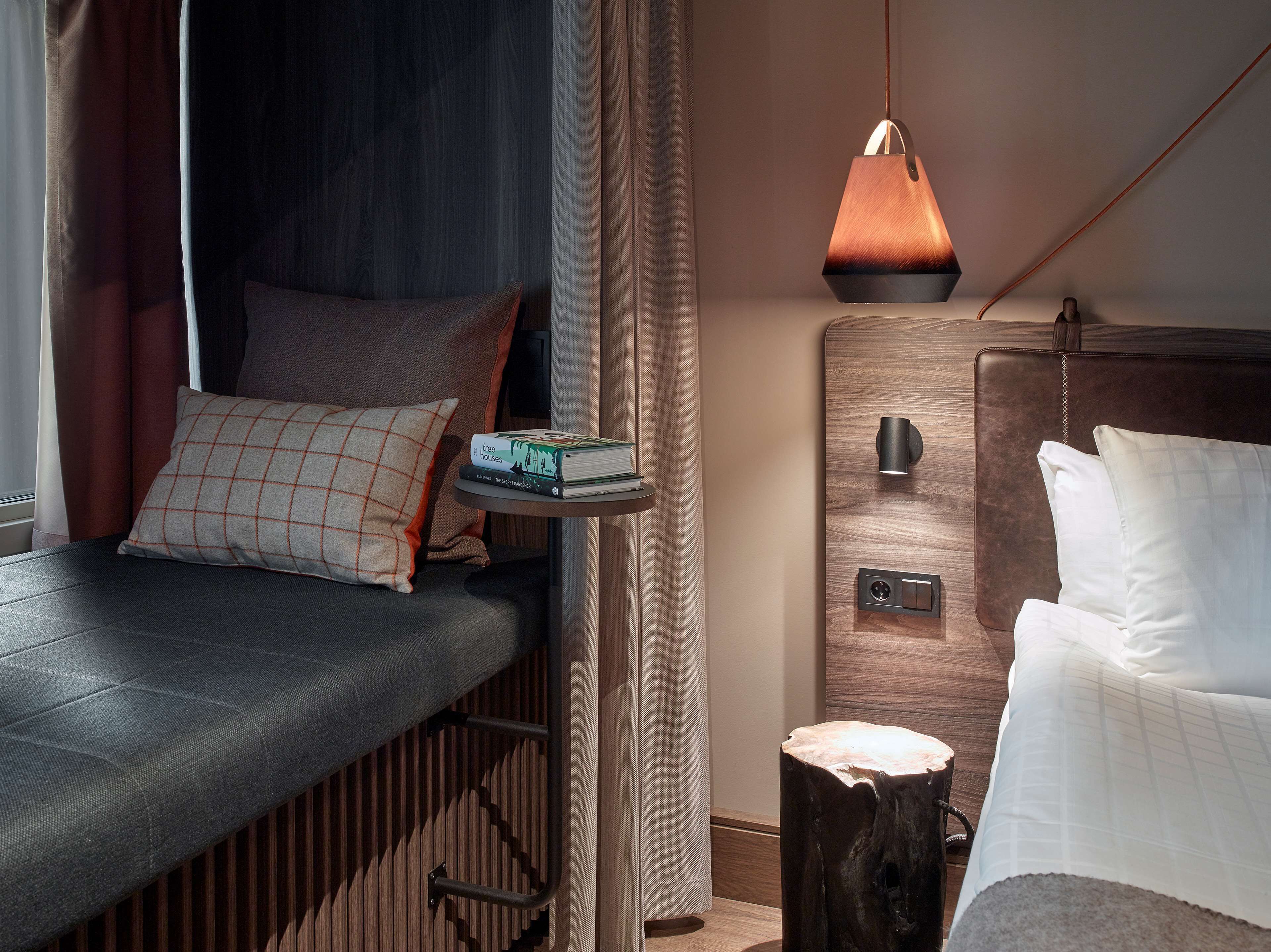 A compact bedroom with a bed, bedside table, and a hanging pendant light.
