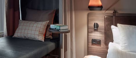 A compact bedroom with a bed, bedside table, and a hanging pendant light.