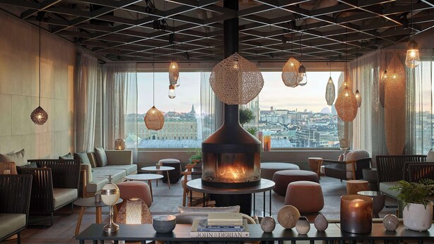 Un área de descanso moderna con chimenea, asientos cómodos e iluminación colgante.