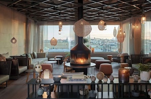 Un área de estar moderna con chimenea, asientos cómodos y vista a la ciudad.