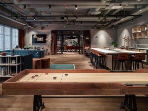 A modern lounge area with a foosball table, seating, and a bar area.