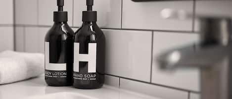 Two bottles of hand soap on a bathroom counter with a white towel and a mirror.