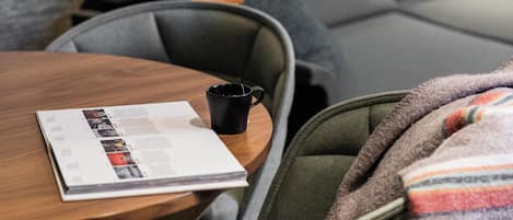 A cozy seating area with a wooden table, a magazine, and a black mug.