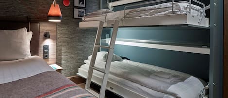 Una cama litera con escalera, una mesita de noche, una lámpara y un estante fijado a la pared.