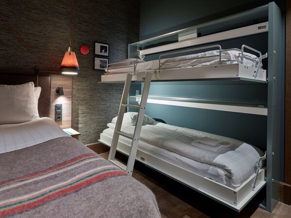 Una cama litera con escalera, una mesita de noche, una lámpara y un estante fijado a la pared.