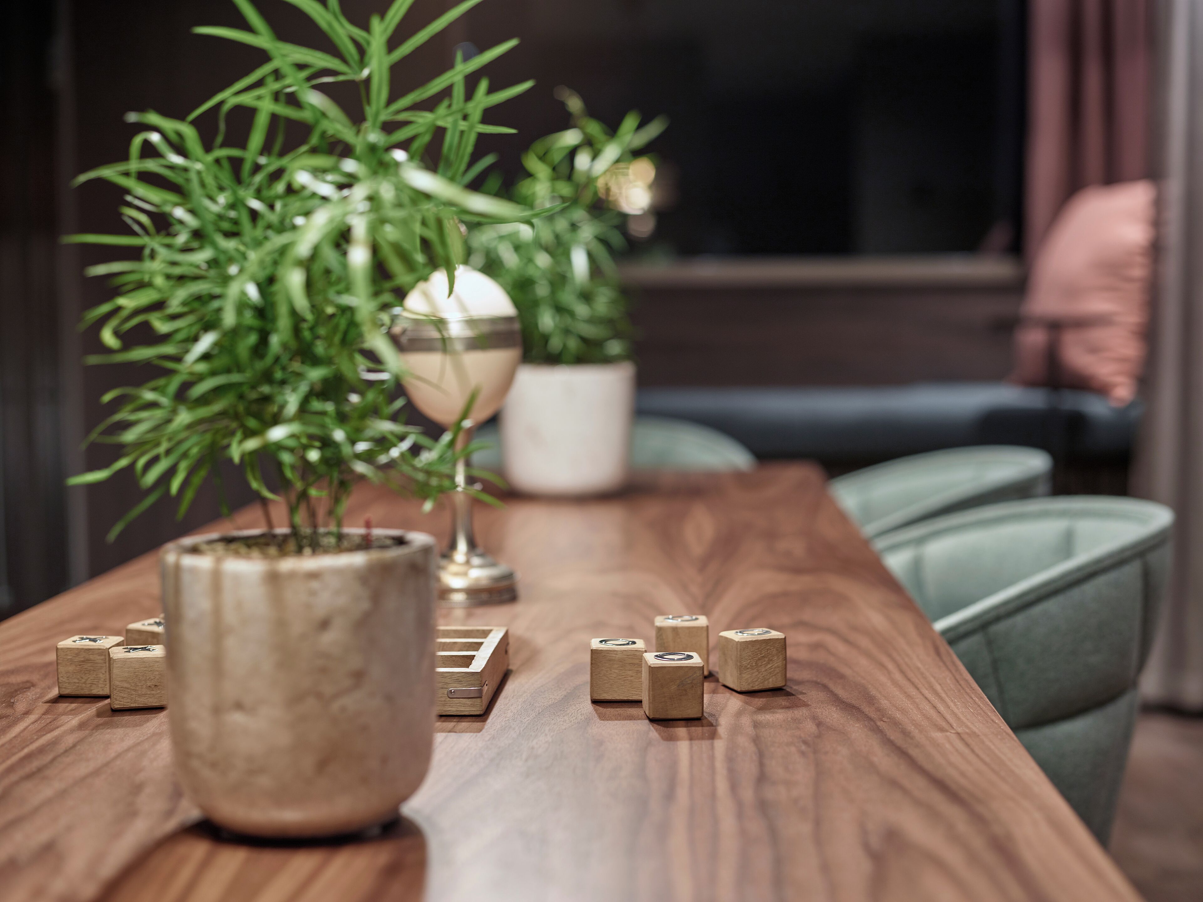A wooden table with a potted plant, a decorative glass vase, and wooden blocks.