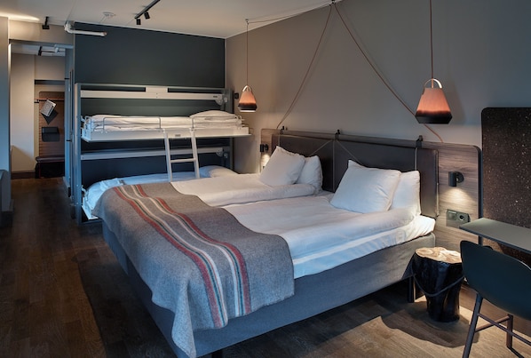 Una habitación de hotel moderna con una litera, una cama individual, un escritorio y una silla.