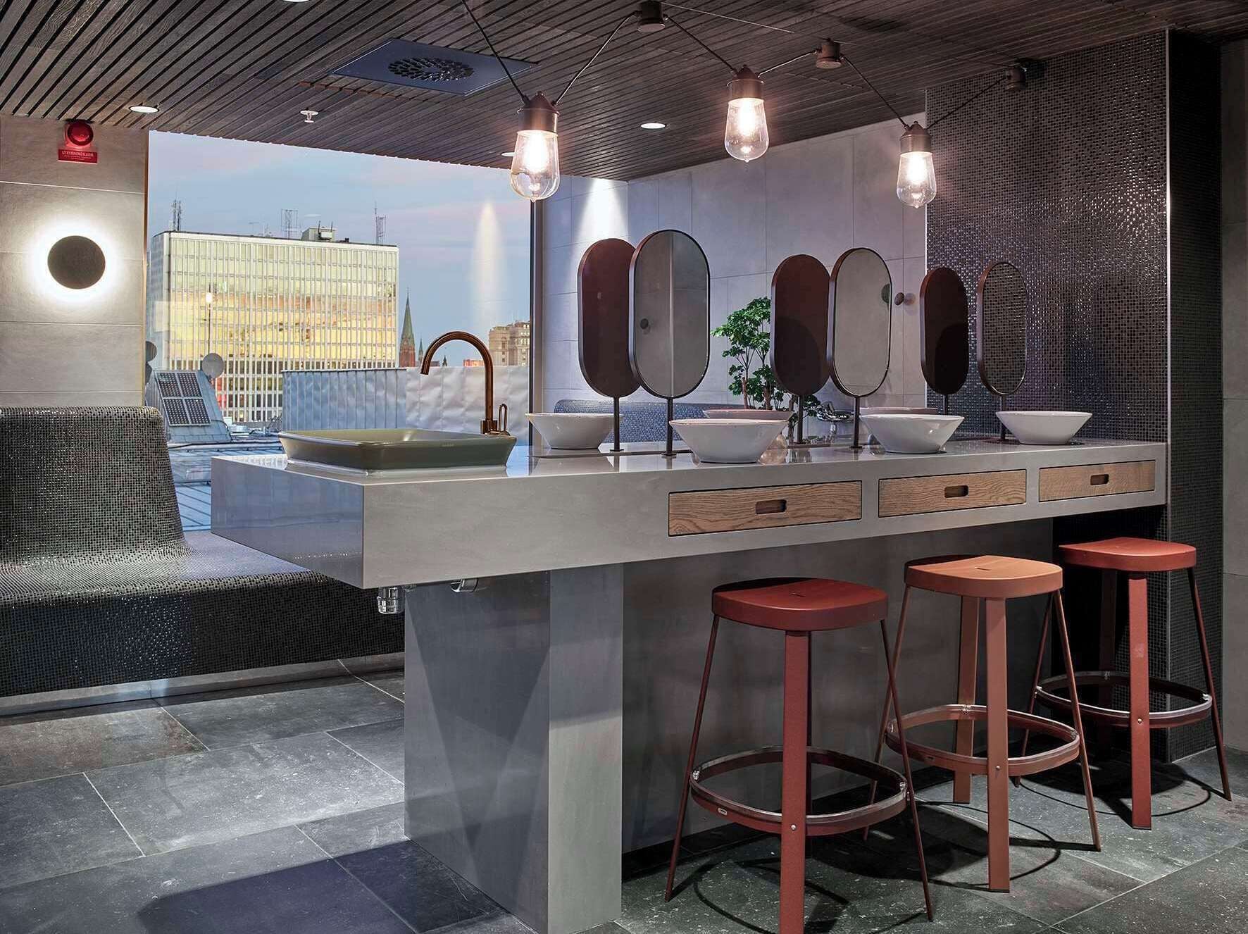 A modern bathroom with a large mirror, a sink, and stools.