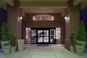 A hotel entrance with a brick facade, a glass door entrance, and potted plants on either side. - Holiday Inn Express & Suites Davis - University Area by IHG (Davis)