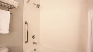 Een badkamer met een bad, een douche en een toilet. Er is een greep bevestigd in de buurt van de douche.