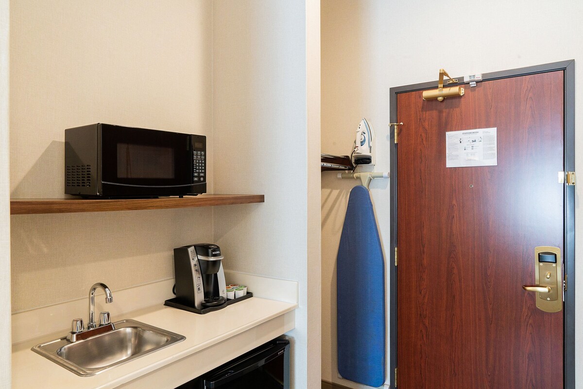 A kitchenette with a microwave, coffee maker, and sink.