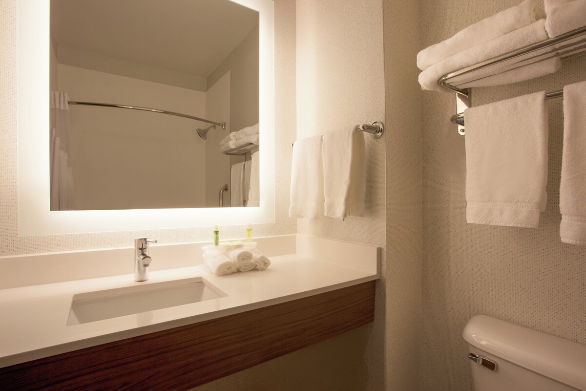 A bathroom with a white sink, a mirror, a towel rack, and a toilet.