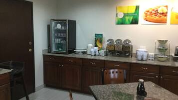 A kitchenette with a coffee machine, a refrigerator, and a breakfast bar.