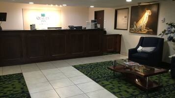A reception area with a wooden reception desk, a chair, a coffee table, and a large giraffe poster on the wall.