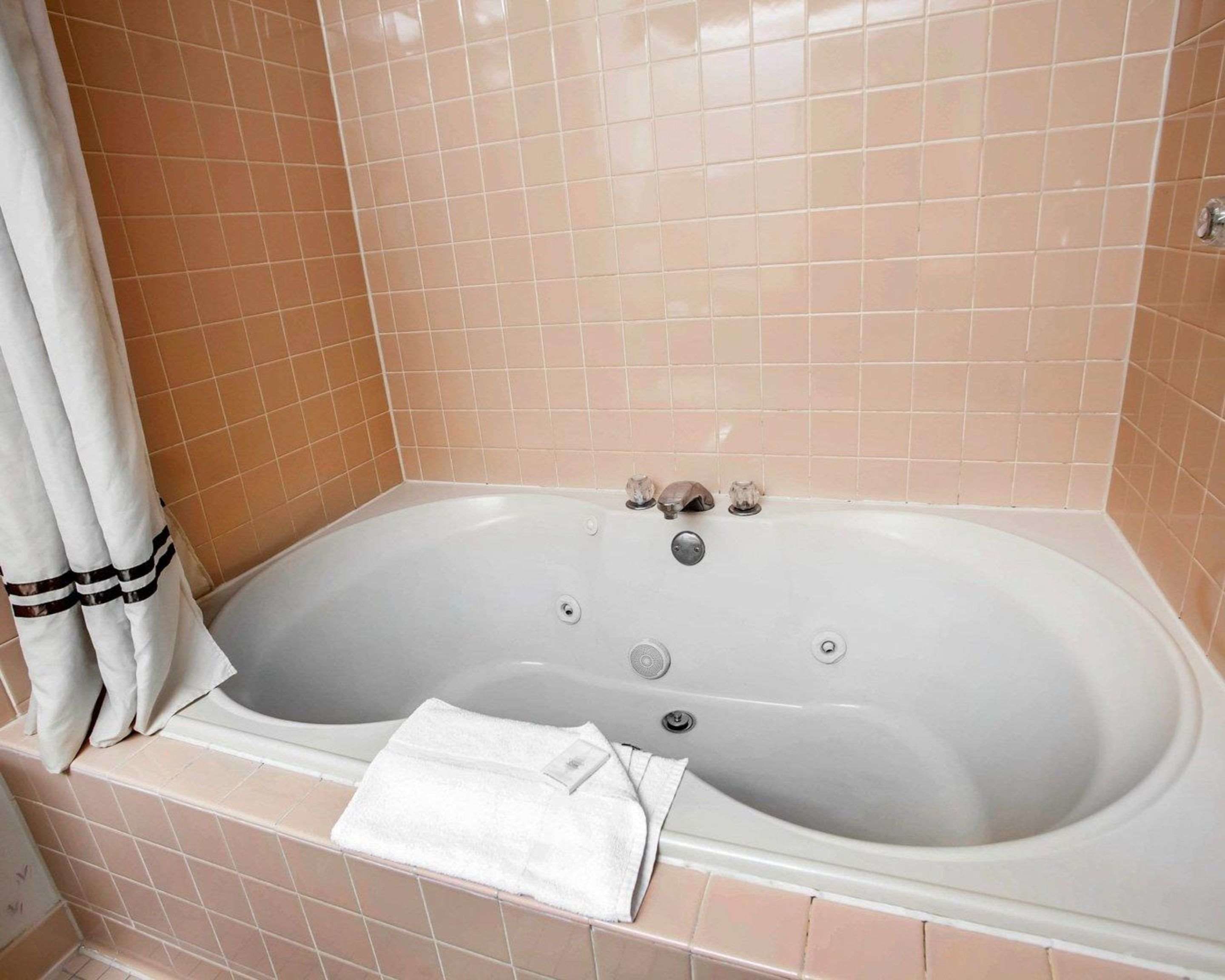 A bathroom with a bathtub, a towel, and a shower curtain.