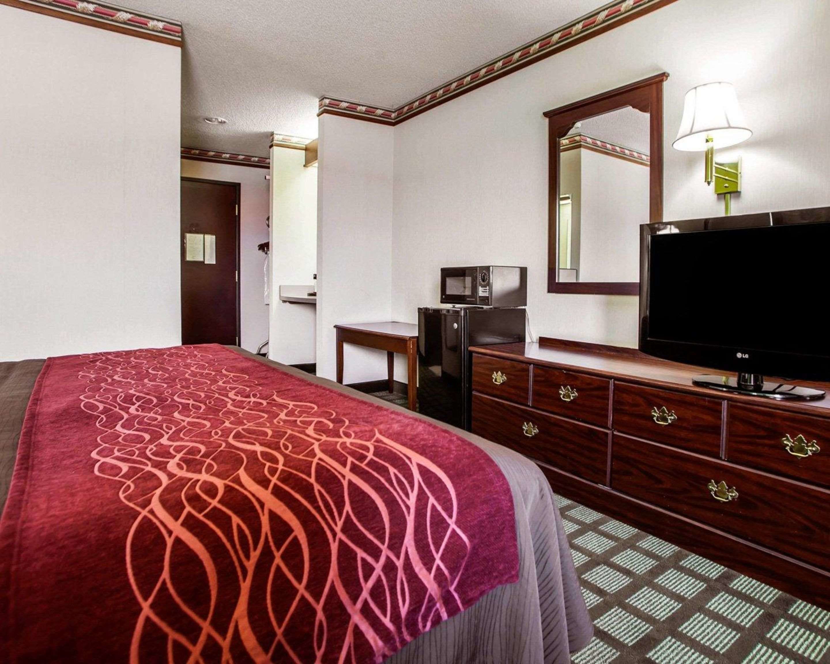 Habitació d'hotel amb un llit, una petita taula de nit, una televisió, un microones i un mirall.