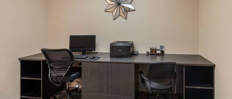 A modern office space with a dark wood desk, two black office chairs, a desktop computer, a printer, and a decorative star-shaped wall art piece.