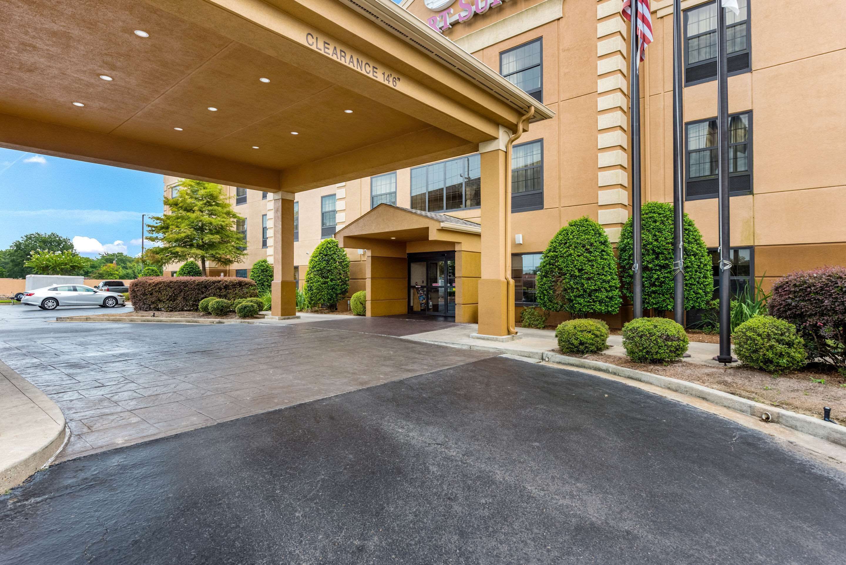 A hotel entrance with a covered walkway, a flagpole, and a clear sky.