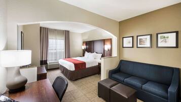 Habitación de hotel con cama, escritorio con teléfono, sofá y pared con cuadros.