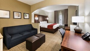 Quarto de hotel com sofá, cama, escrivaninha e cadeira.