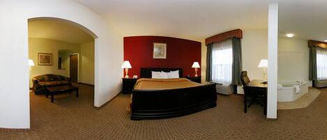 A hotel room with a bed, two bedside tables with lamps, a chair, a desk, and a bathroom with a bathtub.