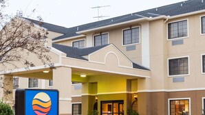 Un hotel Comfort Inn con fachada color beige, varias ventanas y una entrada bien iluminada.
