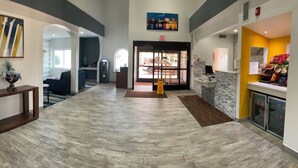 Un hall de hotel con mostrador de recepción, zona de estar y vistas al exterior.