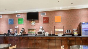 Una barra de desayuno con un televisor de pantalla plana, diversos alimentos y una cafetera.