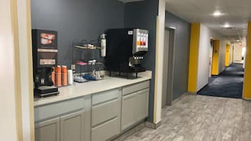 A clean, modern kitchenette with a coffee machine, a water dispenser, and a trash bin.