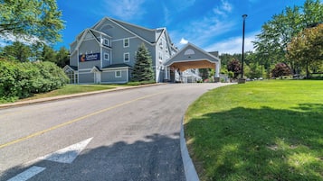 A hotel with a large building, a covered entrance, and a well-maintained lawn.
