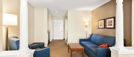 A hotel lobby with a blue sofa, a wooden coffee table, and a lamp.