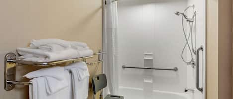 Een moderne badkamer met een inloopdouche, handgrepen, een rolstoeltoegankelijke bank en netjes opgevouwen handdoeken.