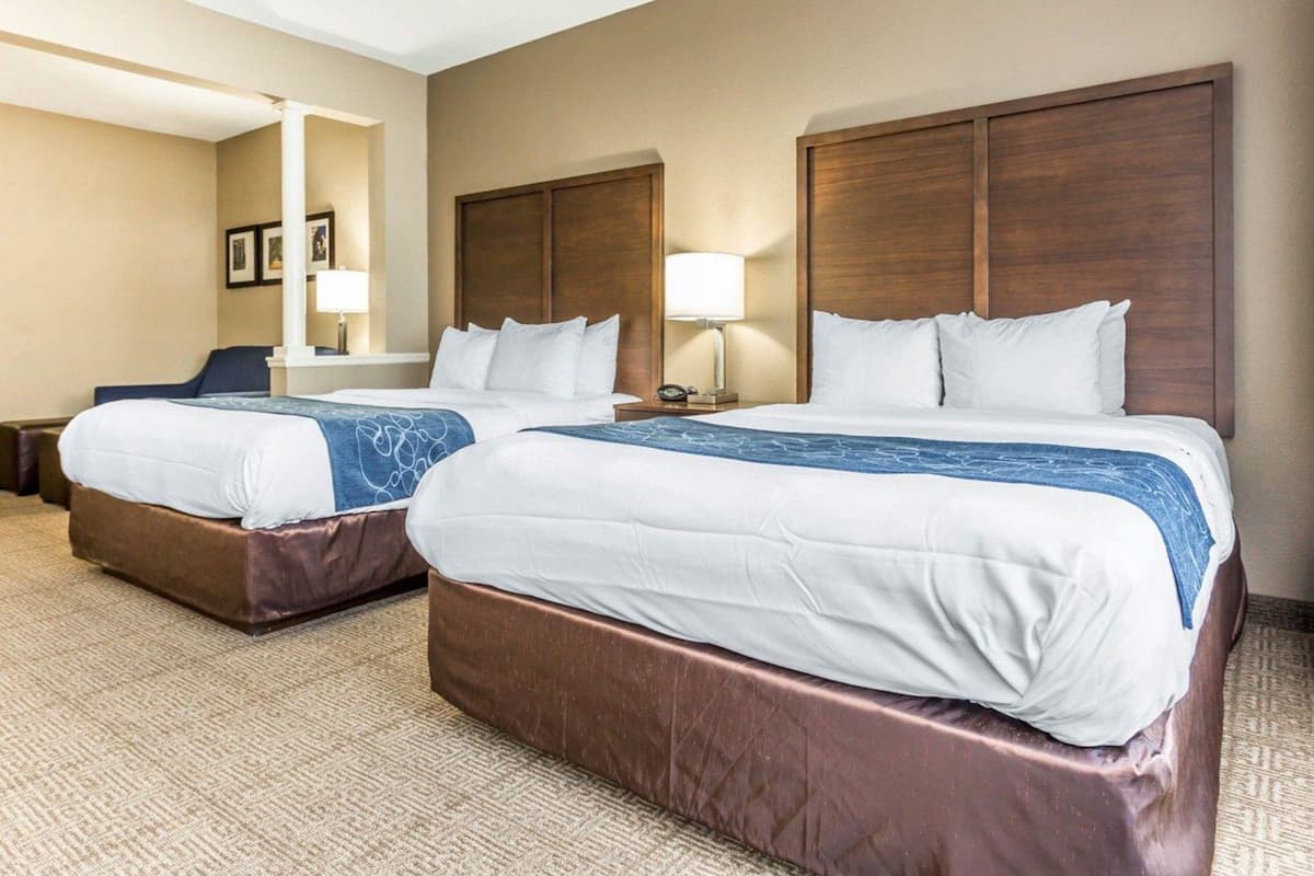 A hotel room with two beds, a desk, and a chair.