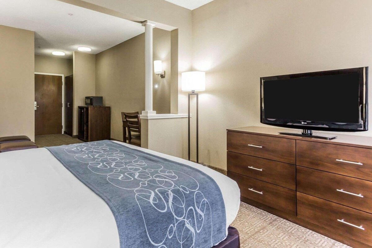 A hotel room with a bed, a television on a dresser, a desk, and a chair.