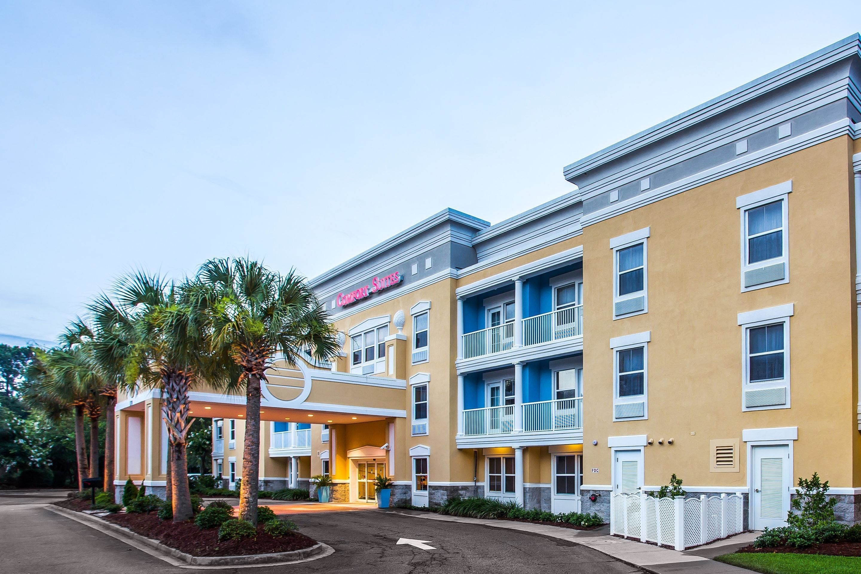 A hotel with a yellow facade, multiple balconies, and a covered entrance area.