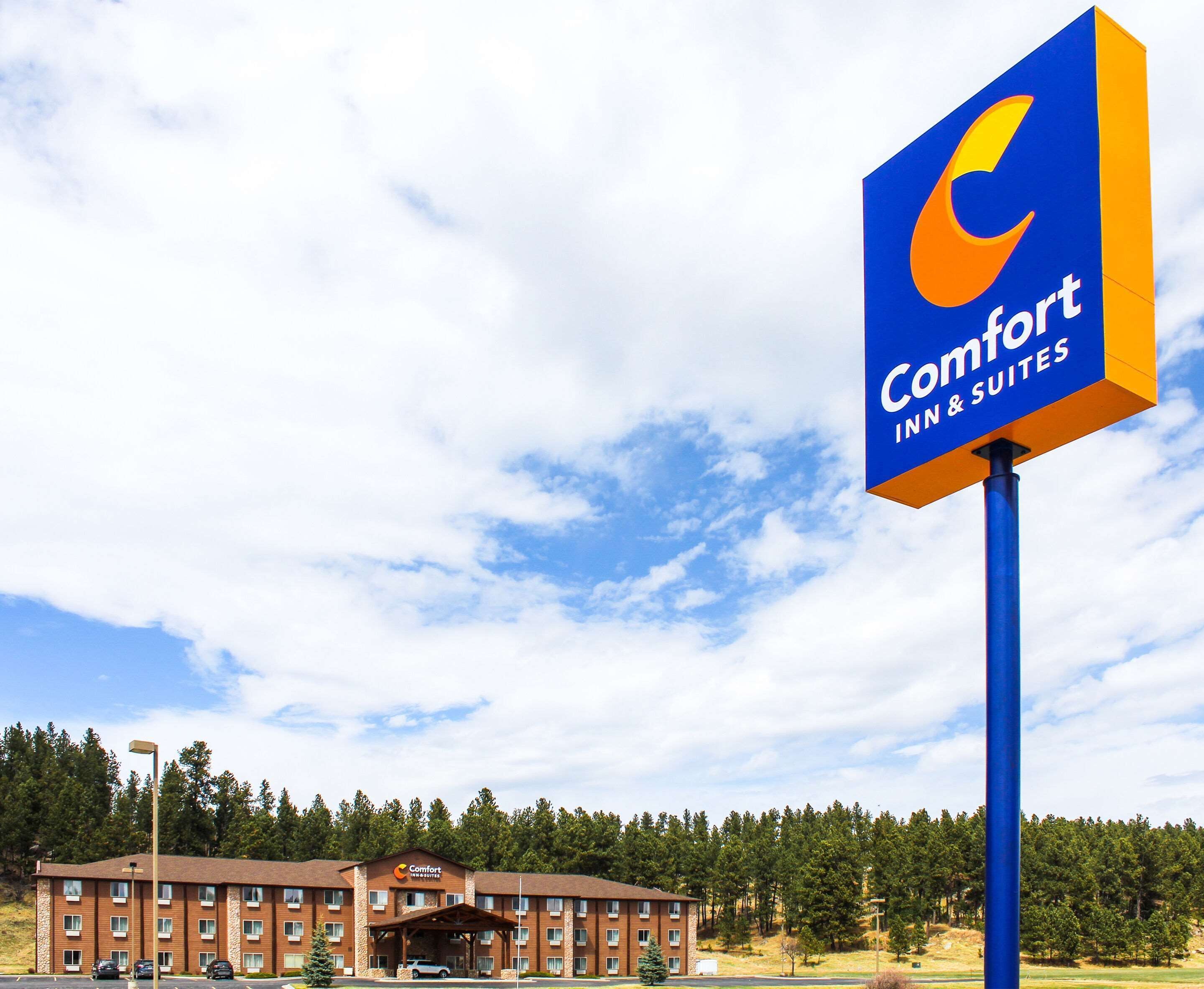 Un hôtel Comfort Inn & Suites, reconnaissable à son enseigne bleue et orange bien visible, à son bâtiment en briques et à son parking.