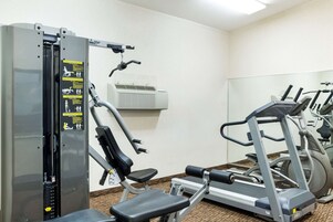 Un gimnasio con una máquina de pesas, una cinta de correr y una bicicleta estática.