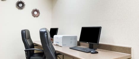 A workspace with two black office chairs, a desktop computer, and a monitor.