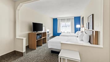 Una habitación de hotel con cama, televisión, escritorio y ventana con cortinas.