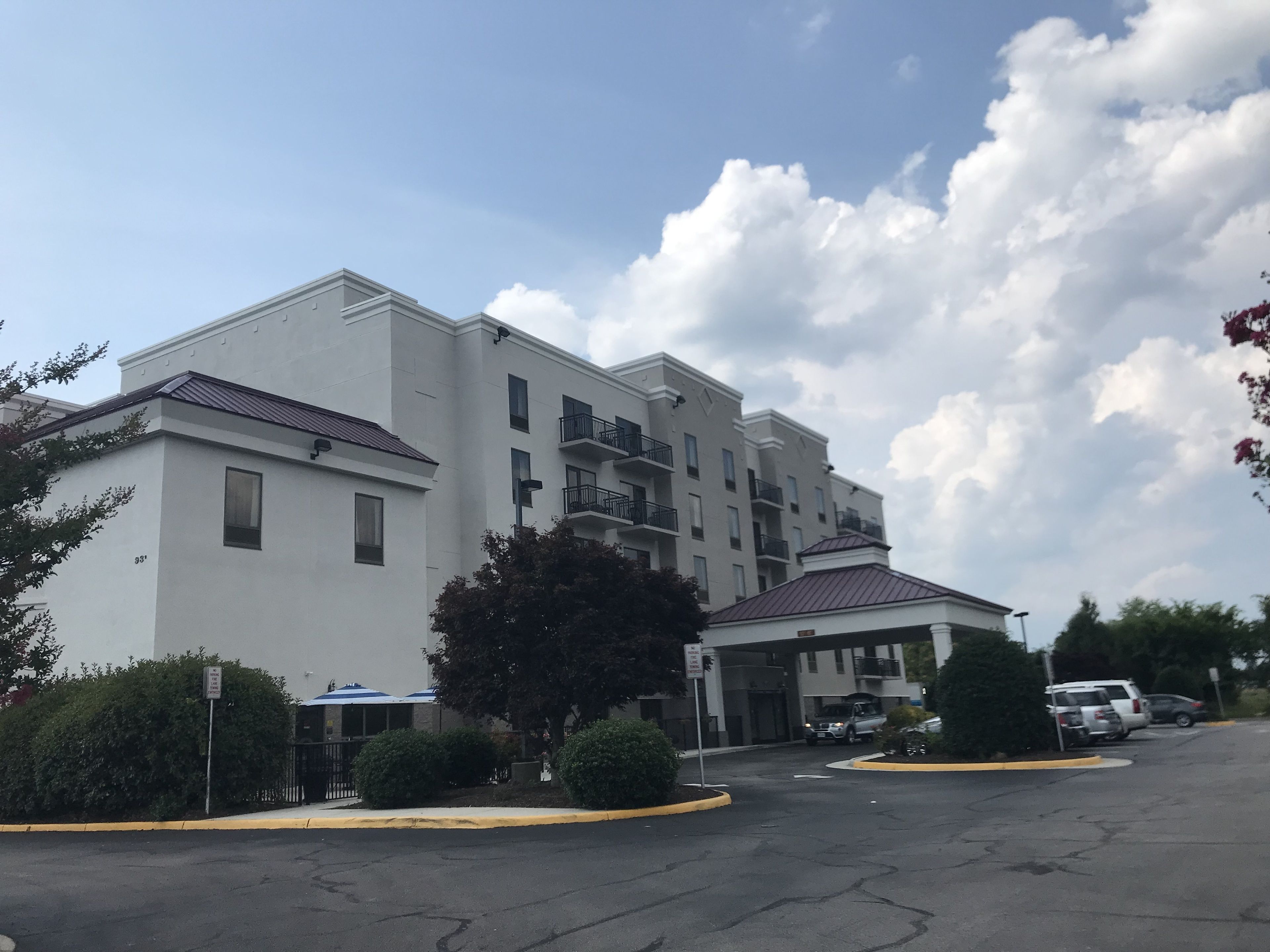 A multi-story hotel with a flat facade, balconies, and a parking lot.