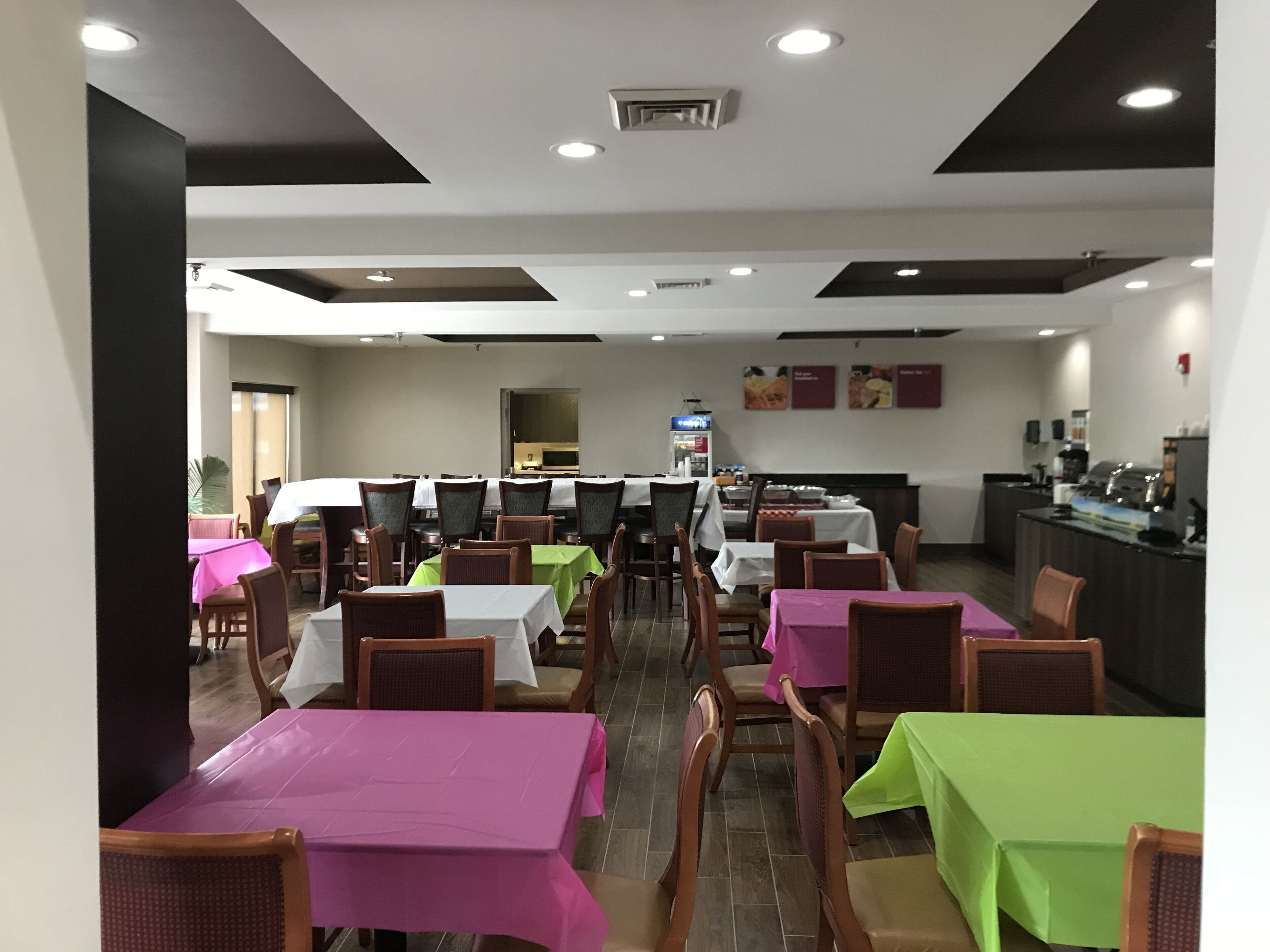 A restaurant with multiple tables and chairs, a kitchen area, and a counter.