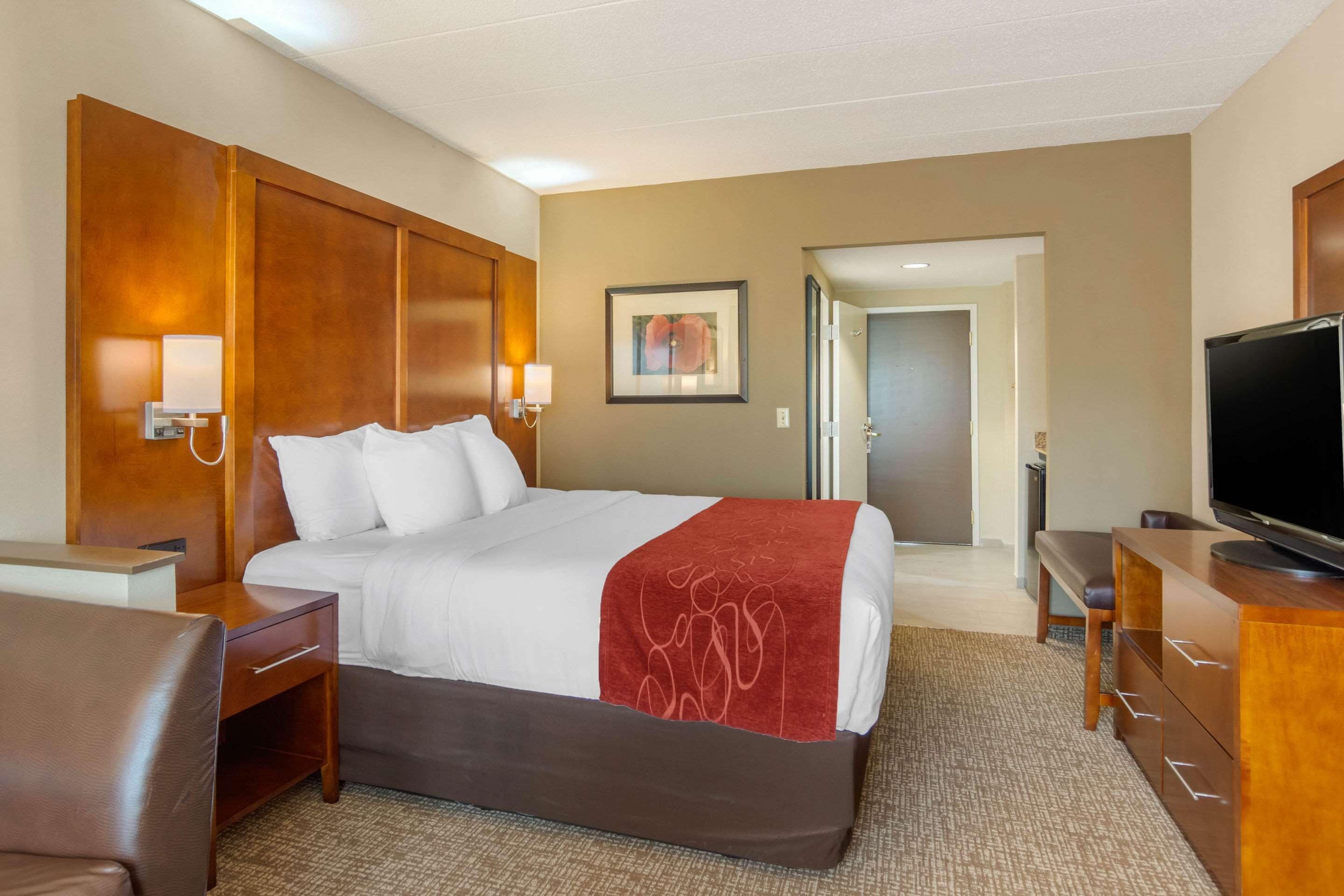A hotel room with a large bed, a TV, a desk, and a chair.