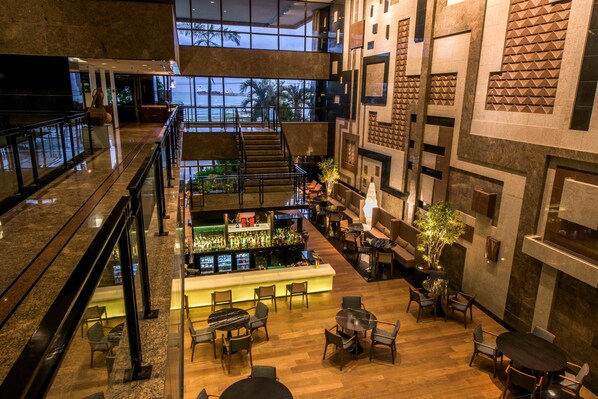 A multi-level hotel lobby with a bar area, seating arrangements, and a view of the outdoors. - Hotel Gran Marquise (Fortaleza)